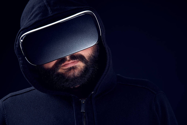 Young hipster bearded man wearing virtual reality goggles. Black background studio VR concept - Valokuva, kuva