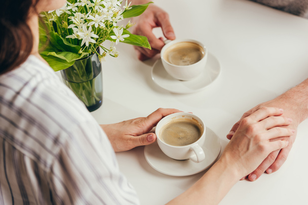 couple drinking coffee and holding hands - Фото, зображення
