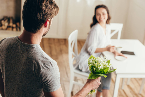 man presenting flowers to girlfriend at home - Foto, Imagen