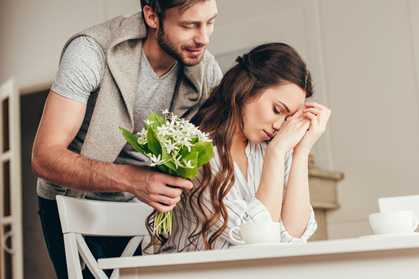 man presenting flowers to girlfriend at home - Photo, Image