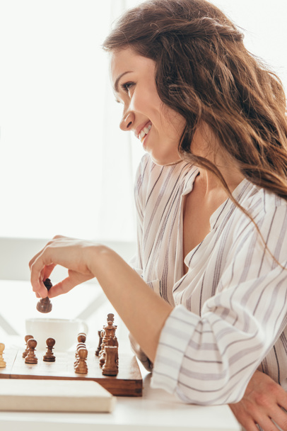 smiling woman moving chess figure - Zdjęcie, obraz