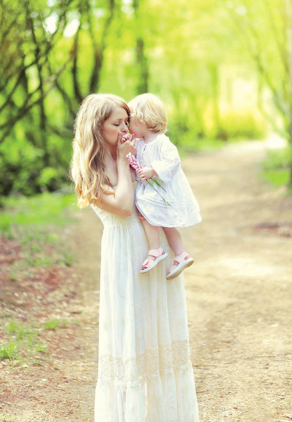 Happy young mother is tenderly kissing her baby holding on the h - Photo, Image