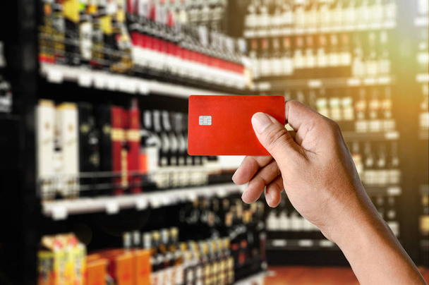 una tarjeta de crédito de mano en el fondo de la tienda Wine Supermarket
 - Foto, Imagen