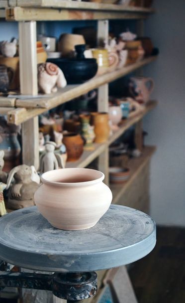 La cacerola de barro en primer plano y las baldas con la cerámica - en segundo lugar
 - Foto, imagen