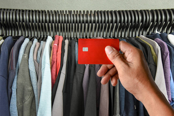 ręki trzymającej karty kredytowej na stojaku t-shirty w sklepie - Zdjęcie, obraz