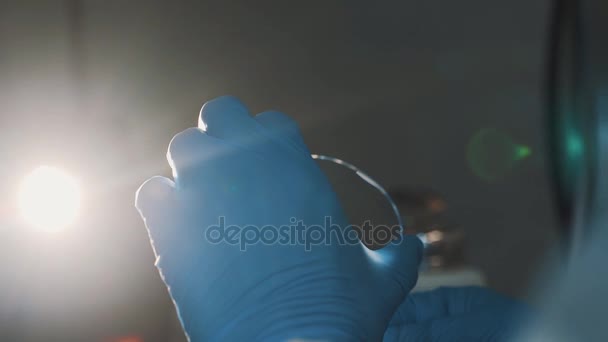 Wetenschapper jat glas met wattenstaafje op laboratorium in heldere lamp licht - Video