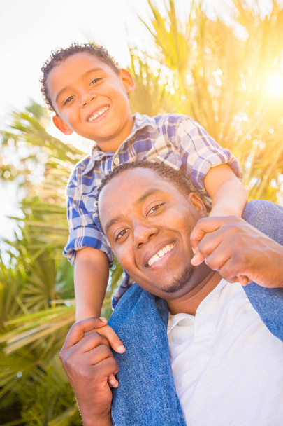 Hijo de raza mixta y padre afroamericano jugando al Piggyback al aire libre juntos
. - Foto, Imagen