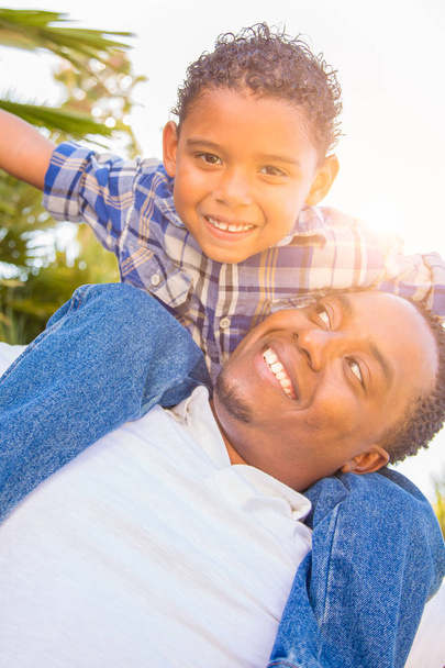 Zoon van gemengd ras en Afrikaanse Amerikaanse vader samenspelen Piggyback buitenshuis. - Foto, afbeelding