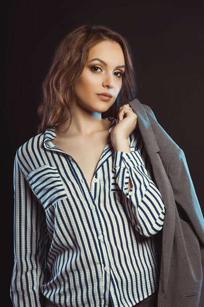 Glamor brunette model posing in shirt and holding her jacket - Foto, Bild