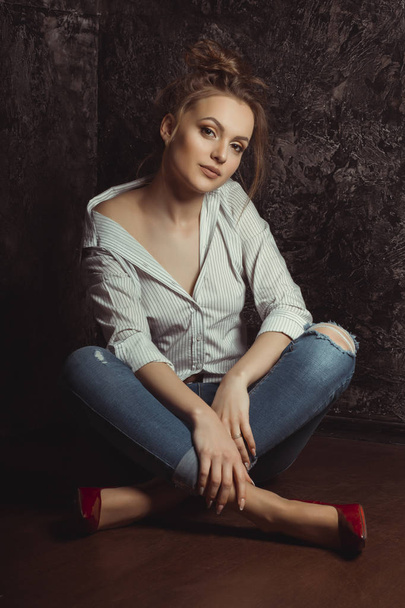 Amazing young woman in shirt and jeans sitting on the floor - Foto, afbeelding