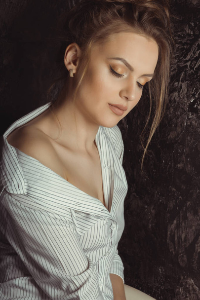 Tierna joven modelo en camisa posando en el estudio con los ojos cerrados
 - Foto, imagen