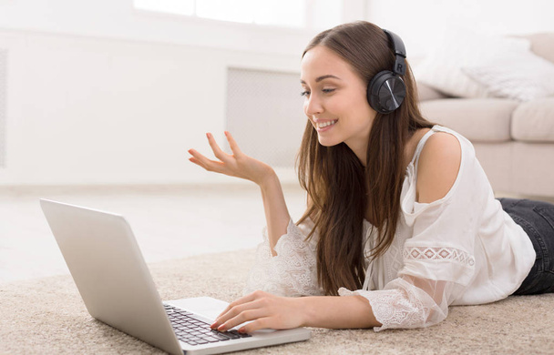 Young girl in headphones. Online on laptop - Фото, изображение