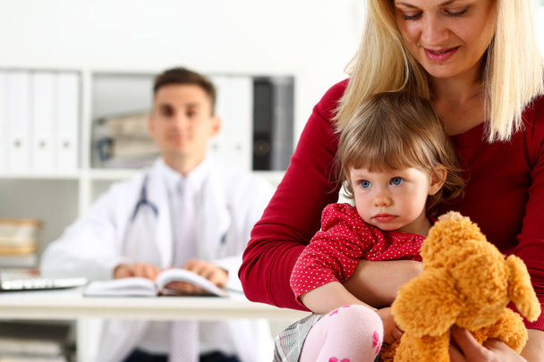 Criança pequena com mãe em recepção de pediatra
 - Foto, Imagem