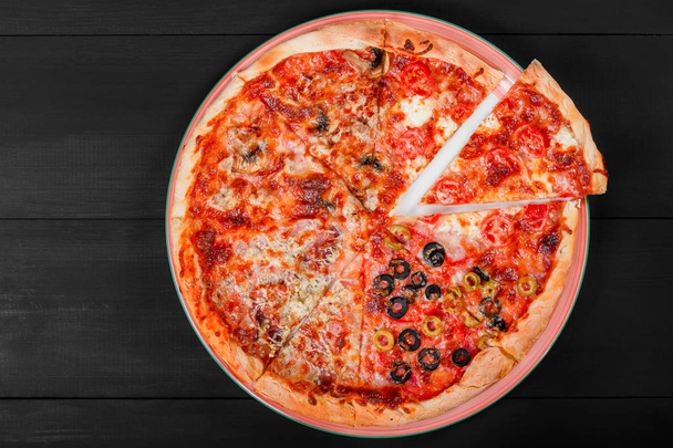 Pizza mixta comida italiana con pollo, tomate, champiñones, jamón, salami, oliva y queso sobre fondo de madera oscura. Pizza casera. Vista superior
 - Foto, imagen