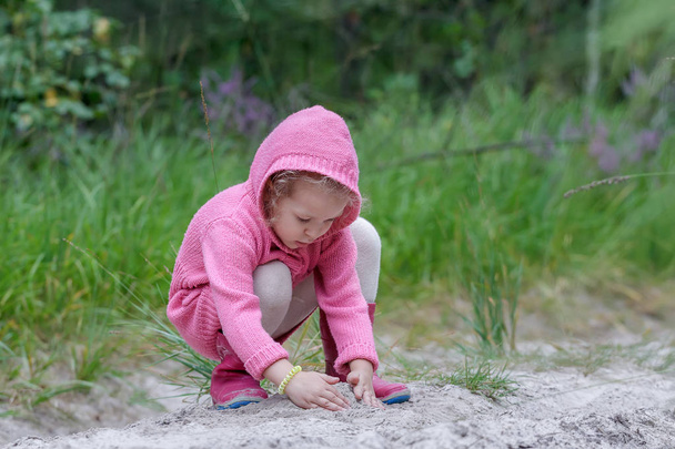 Niña jugando con arena en el bosque de verano
 - Foto, imagen