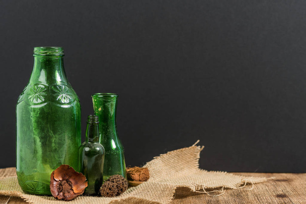 Зеленые винтажные бутылки на мешковине с сушеными семенами и цветами
 - Фото, изображение
