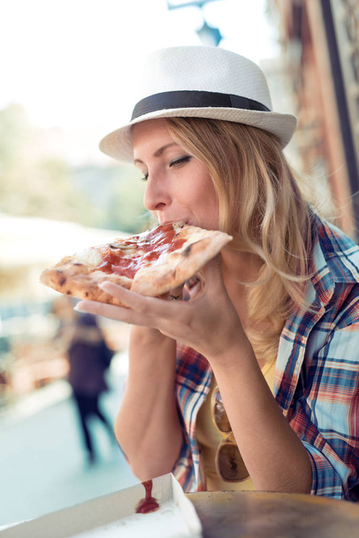 woman enjoying slice of pizza - Foto, afbeelding