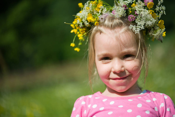 Retrato de una niña rubia con una corona de flores en la cabeza
 - Foto, Imagen