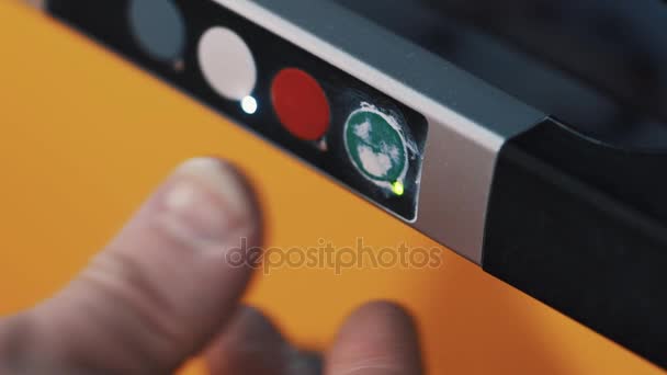 Le pouce de la main du travailleur appuie sur le bouton vert du panneau de commande de l'installation
 - Séquence, vidéo