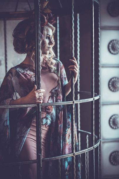 Luxurious  fashion stylish girl  in cage. Flower dress and a wr - Фото, зображення