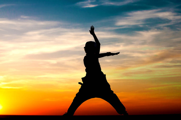 силует маленької дівчинки робить вправи йоги на фоні заходу сонця неба
 - Фото, зображення