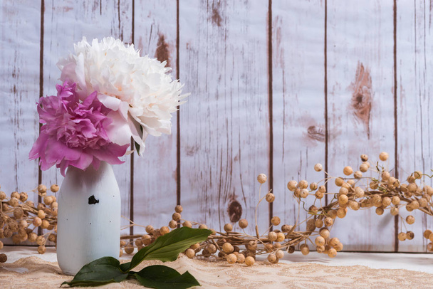 Peony bloemen in een fles melk met houten achtergrond - Foto, afbeelding