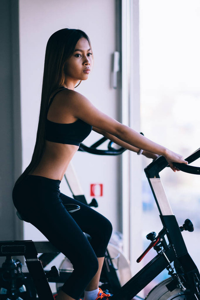 Sport young woman on a stationary bike in the gym - Photo, Image