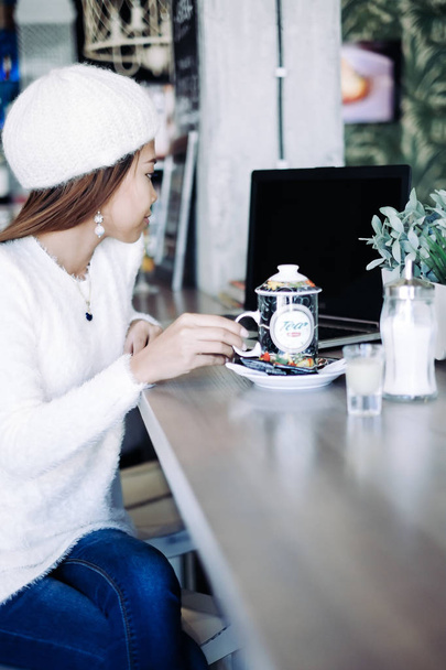 Mladá žena v kavárně pití čaje. Mladá žena s laptopem v kavárně - Fotografie, Obrázek