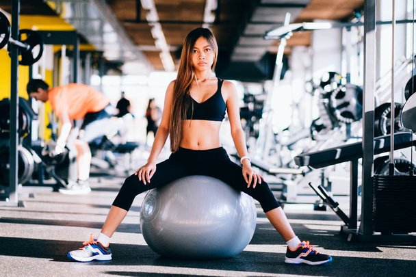 Fitness young woman with long hair in gym, sitting on Pilates ball - Foto, Bild