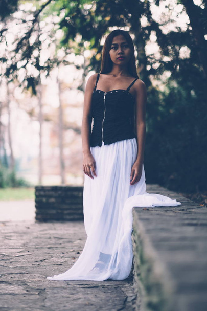 Beautiful girl in long white dress, daydreaming in the park  - Fotó, kép