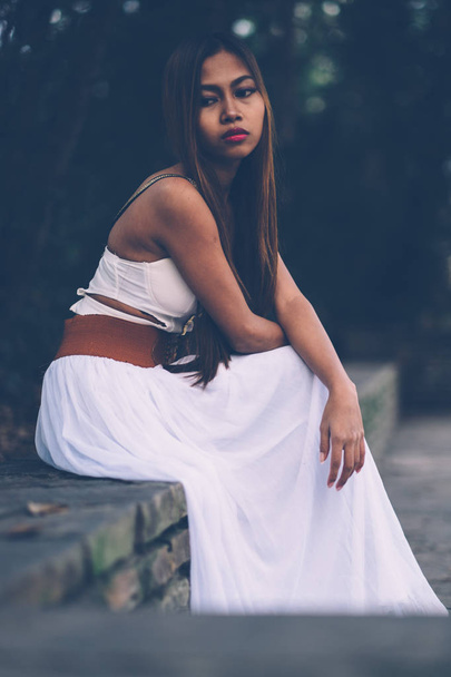 Beautiful girl in long white dress sitting, daydreaming in the park  - Foto, Imagem