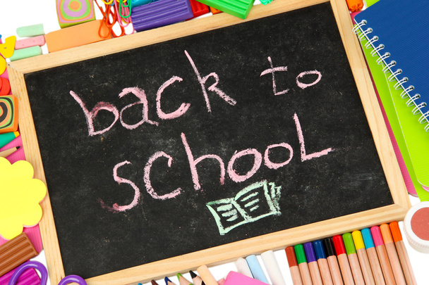 The words 'Back to School' written in chalk on the small school desk with various school supplies close-up - Foto, Imagen