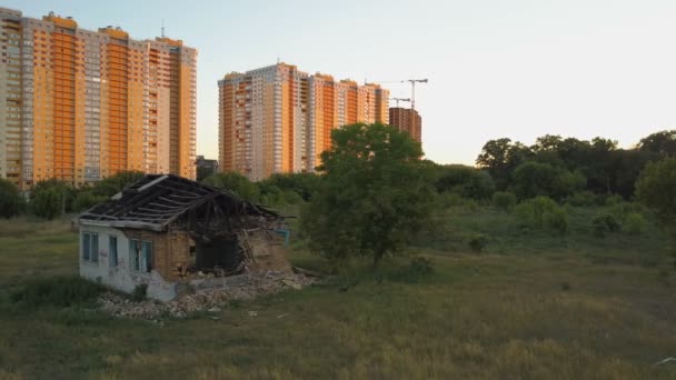 Samotny stary zniszczony dom stoi w pobliżu z nowe mieszkania w budynkach wielopiętrowych. Widok z lotu ptaka - Materiał filmowy, wideo