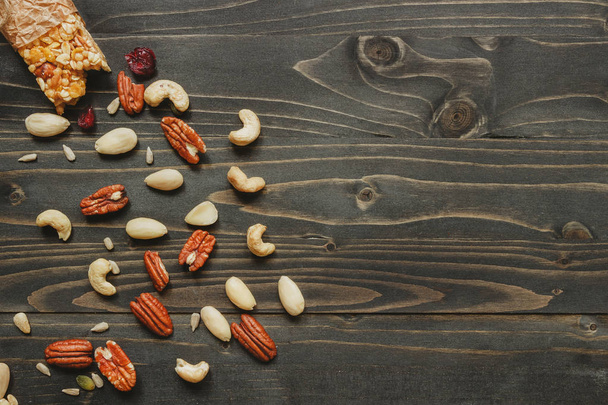 Healthy bar with nuts and seeds on the wooden background, top view. Copy space - Zdjęcie, obraz