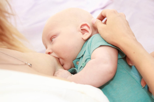 indoor portret van de moeder borstvoeding geeft - Foto, afbeelding