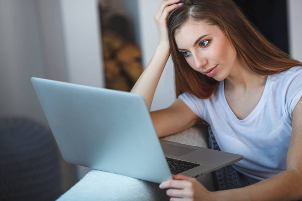 young woman sitting with laptop on sofa at her home - Photo, Image