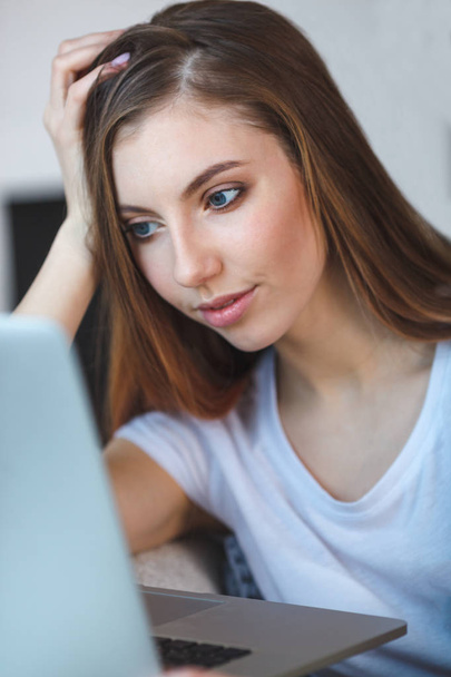 mujer joven sentada con el ordenador portátil en el sofá en su casa
 - Foto, imagen