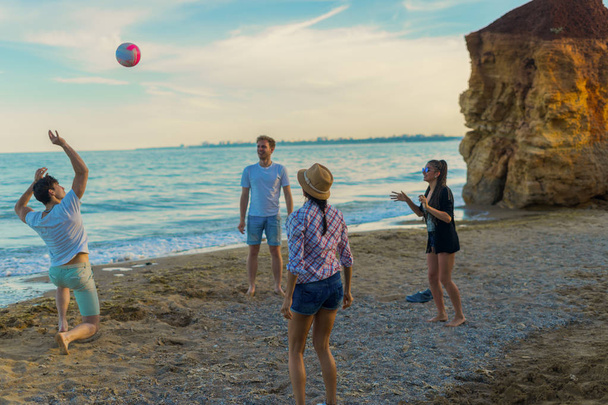 przyjaciele, gry w siatkówkę na dzikiej plaży podczas zachodu słońca - Zdjęcie, obraz