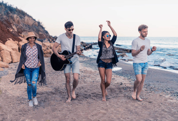 grupo de jovens e alegres amigos andando na praia
 - Foto, Imagem