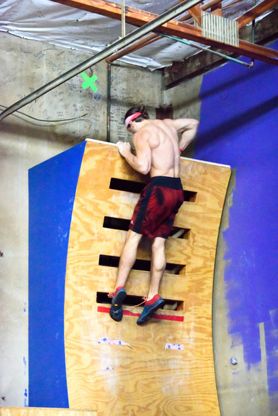 Giovane atleta guerriero ninja maschio, Adam Rahl, cercando di scalare il muro di curvatura durante una gara di guerrieri ninja del 2017
  - Foto, immagini