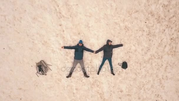 couple lying in the snow,shooting with the drone,Aerial view - Footage, Video