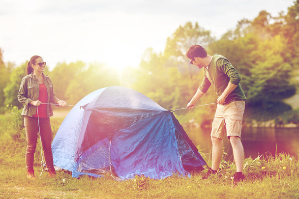 happy couple setting up tent outdoors - Foto, Imagen