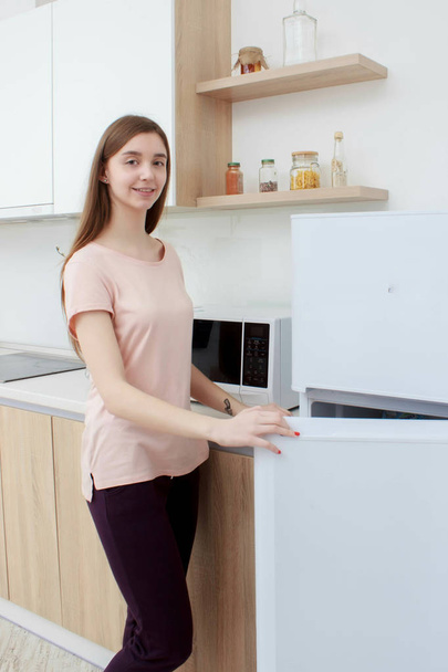 Mujer feliz buscando algo en el refrigerador en casa - Foto, Imagen