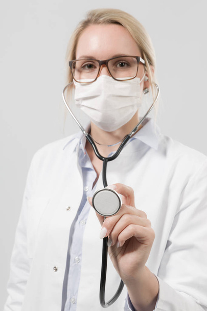 young female doctor with stethoscope and medical face mask - Foto, imagen