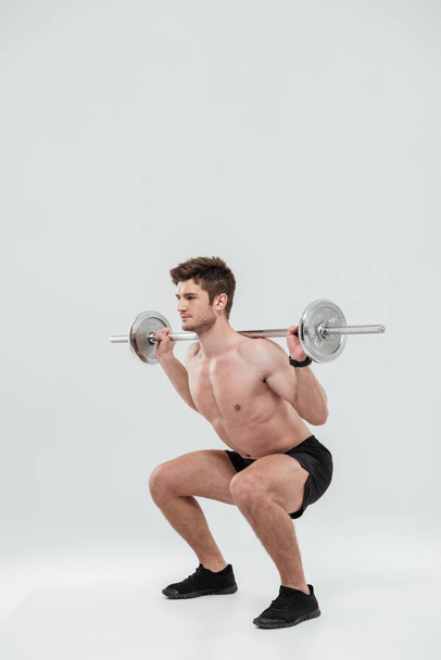 Young healthy man athlete doing exercises with barbell - Φωτογραφία, εικόνα
