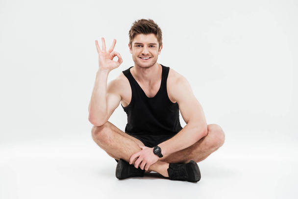Portrait of a young smiling healthy fitness man sitting - Fotó, kép