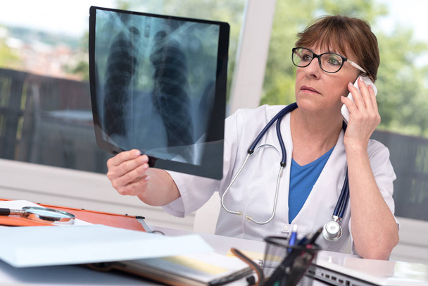 Médecin féminin examinant un rapport de radiographie
 - Photo, image
