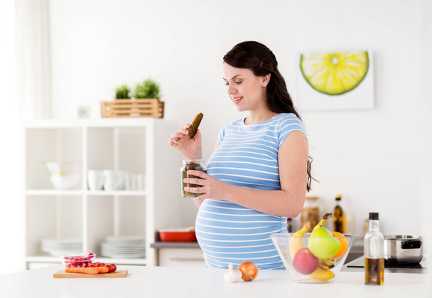 pregnant woman eating pickles at home kitchen - Fotoğraf, Görsel