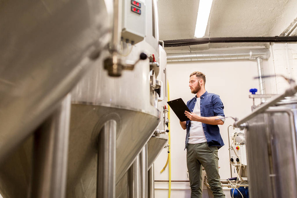 man with clipboard at craft brewery or beer plant - Foto, Bild