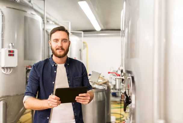 man with tablet pc at craft brewery or beer plant - Photo, image